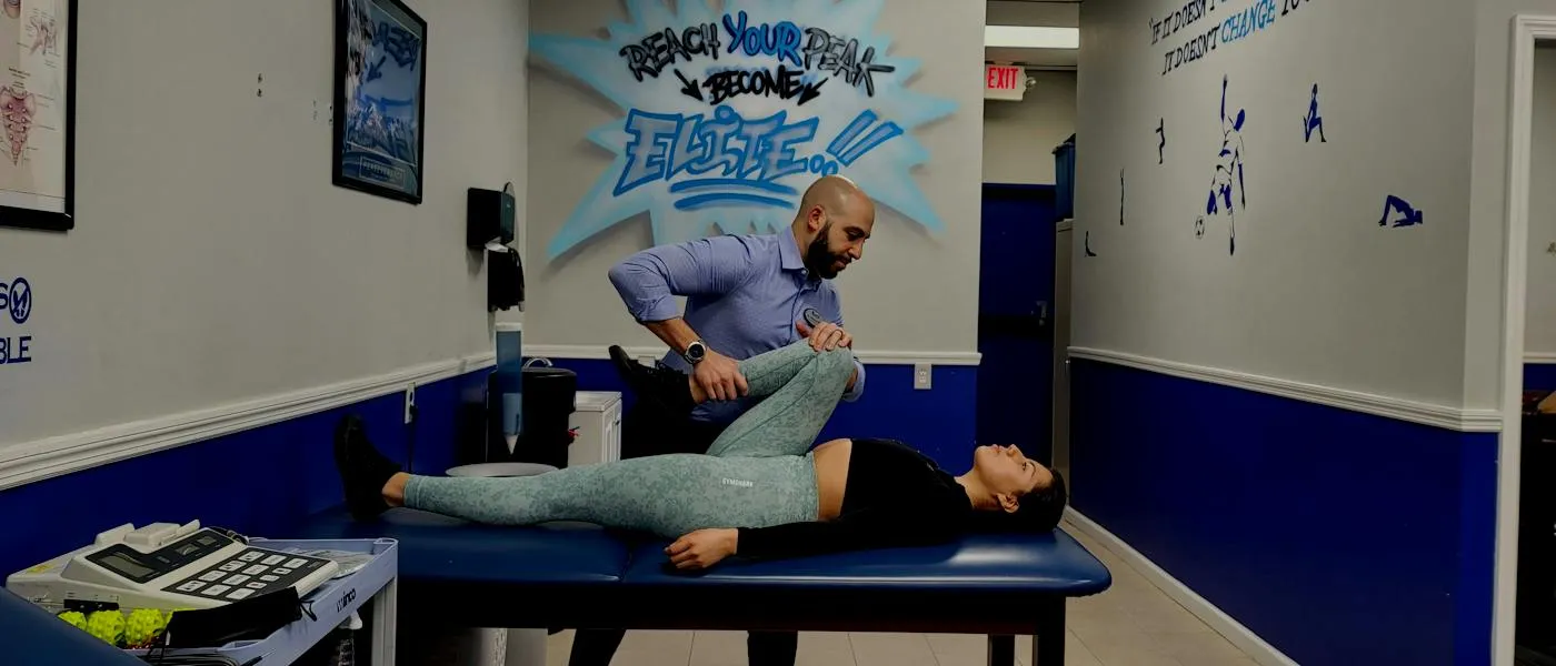 Dr. Mohamed Masoud stretching a patient's leg on a treatment table, under the clinic's graffiti mural that reads “Reach your peak, become Elite”