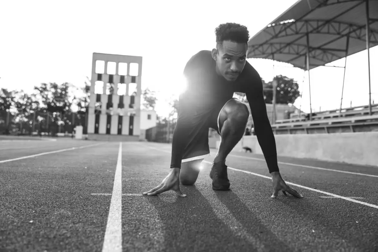 An athlete crouched at the start line of a running track, ready to sprint
