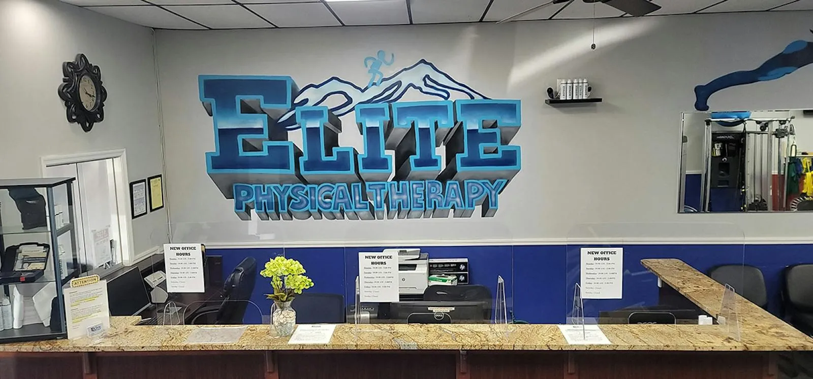 The clinic's front desk under a large graffiti mural of the Elite Physical Therapy logo